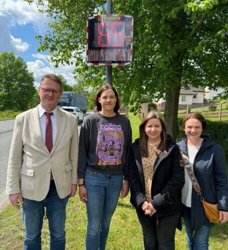 The mayor of Waldkappel, Frank Koch, and deputy Karina Fissmann, accompanied by two parents, in front of the newly installed EVOLIS Vision radar speed sgin in Bischhausen.